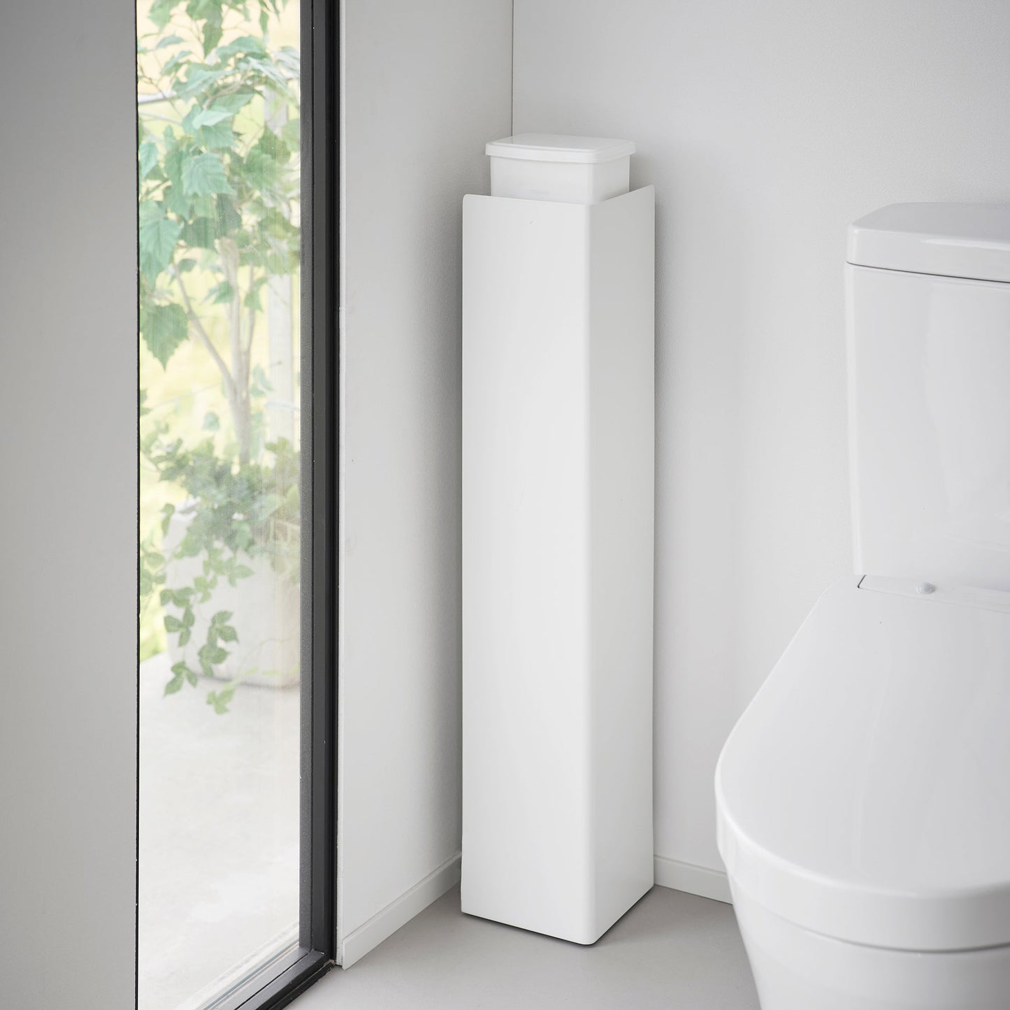 White Yamazaki Home Rolling Bathroom Organizer turned around to conceal the toilet brush and other items stored