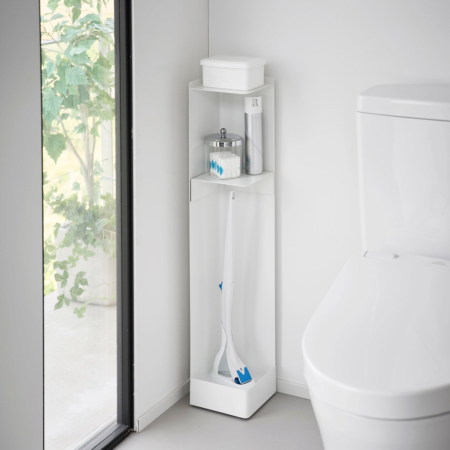 White Yamazaki Home Rolling Bathroom Organizer next to a toilet storing a toilet brush, cleaning spray and wet wipes