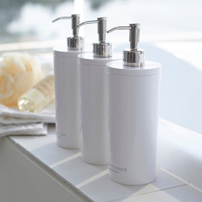 Yamazaki Home white Shampoo, Conditioner, and Body Soap dispensers in bathroom.