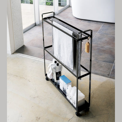 Black Rolling Towel Rack holding towels and cleaning products by Yamazaki Home.