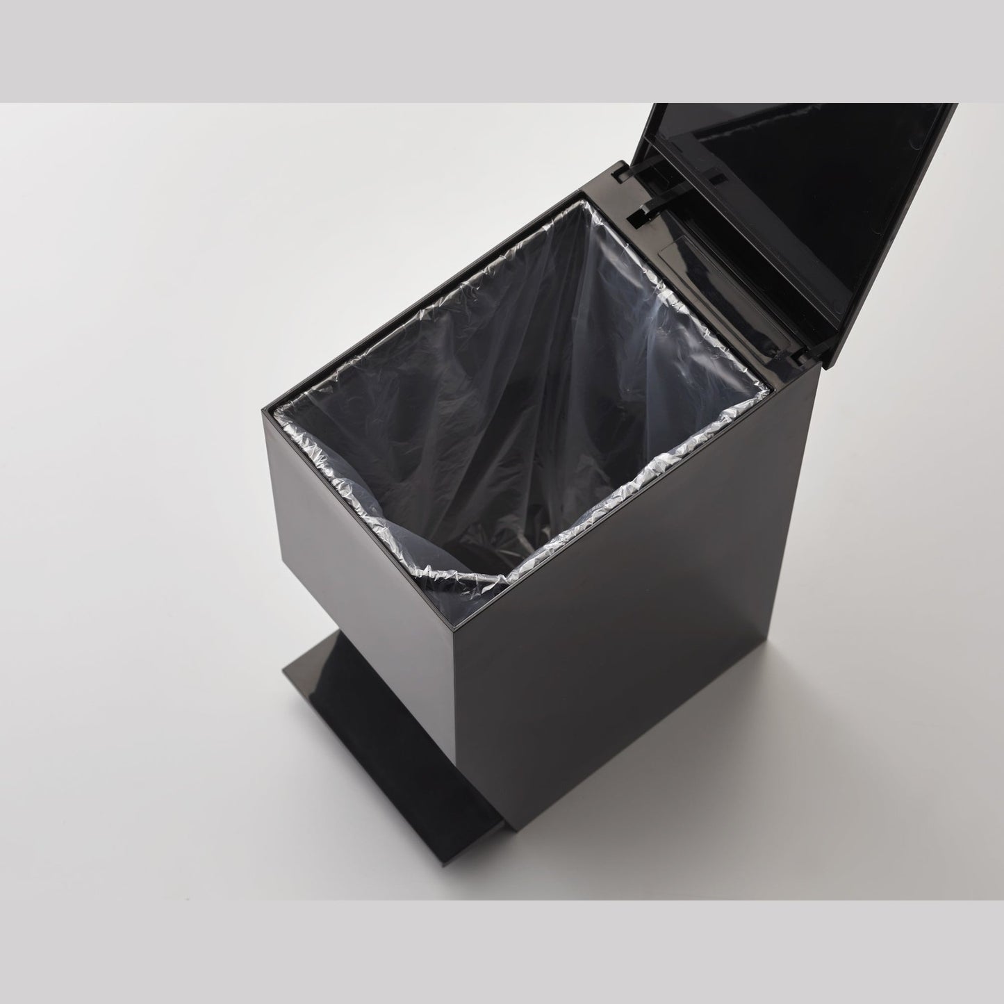 Aerial view of black Trash Can containing plastic bag on white background by Yamazaki Home.