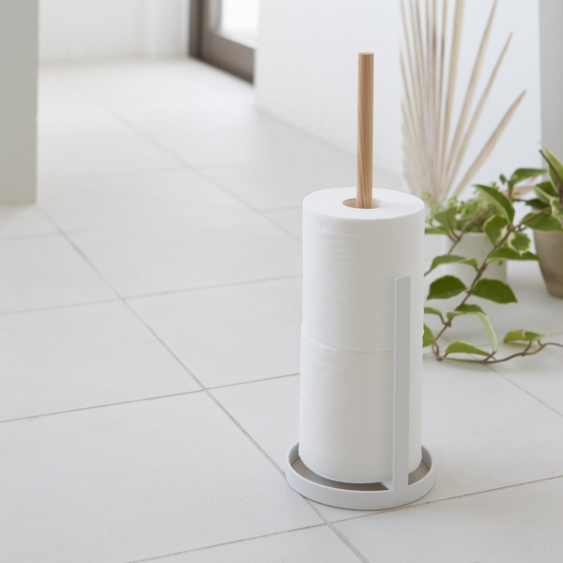 Toilet Paper Stocker holding toilet paper rolls on tile floor by Yamazaki Home.