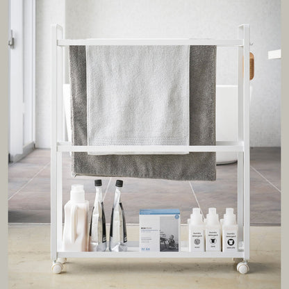Front view of white Rolling Towel Rack holding towels and cleaning products by Yamazaki Home.
