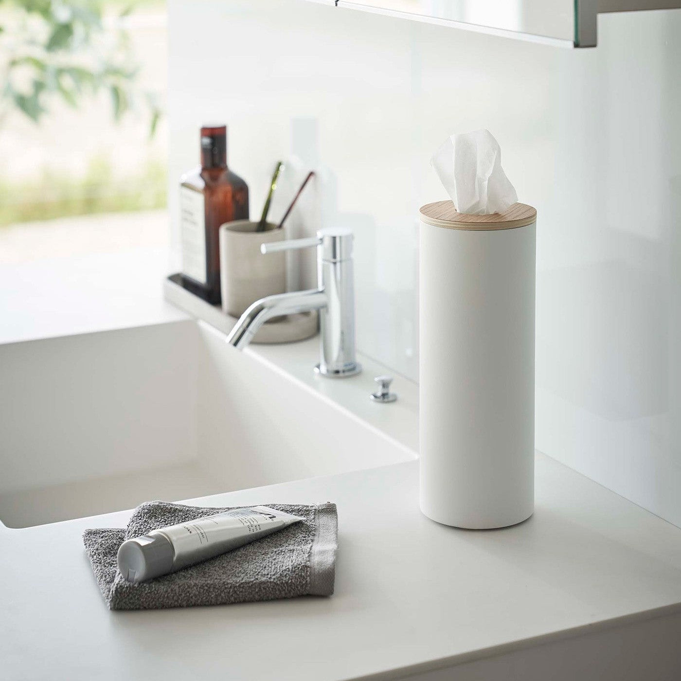 Large White Yamazaki Home Round Tissue Case on a bathroom sink counter