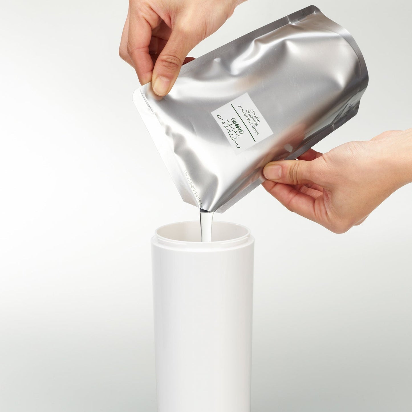 Front view of Shampoo Dispenser with top off getting filled with shampoo on white background by Yamazaki Home.
