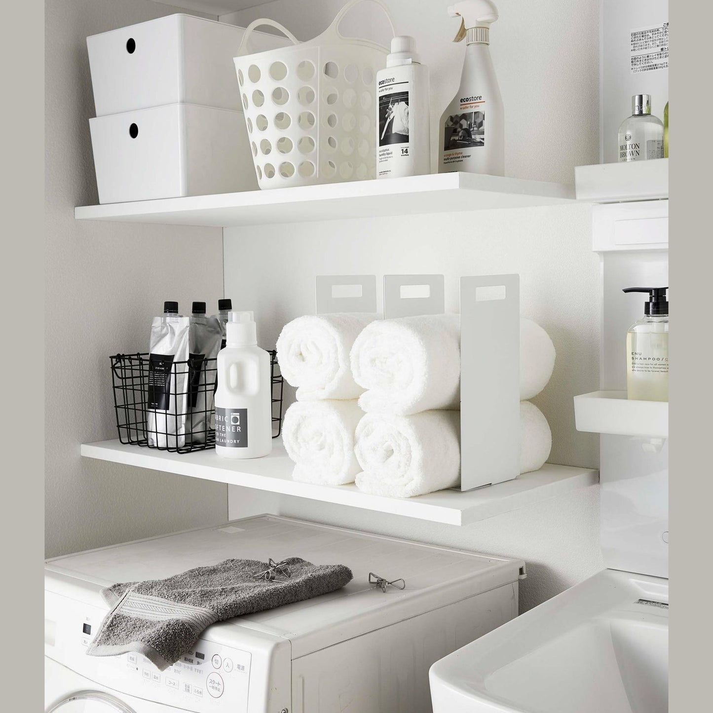 White Towel Storagae Organizers holding towels on laundry room shelf by Yamazaki Home.