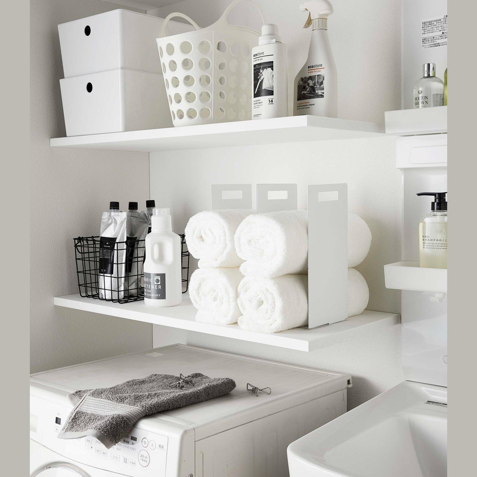 White Towel Storagae Organizers holding towels on laundry room shelf by Yamazaki Home.