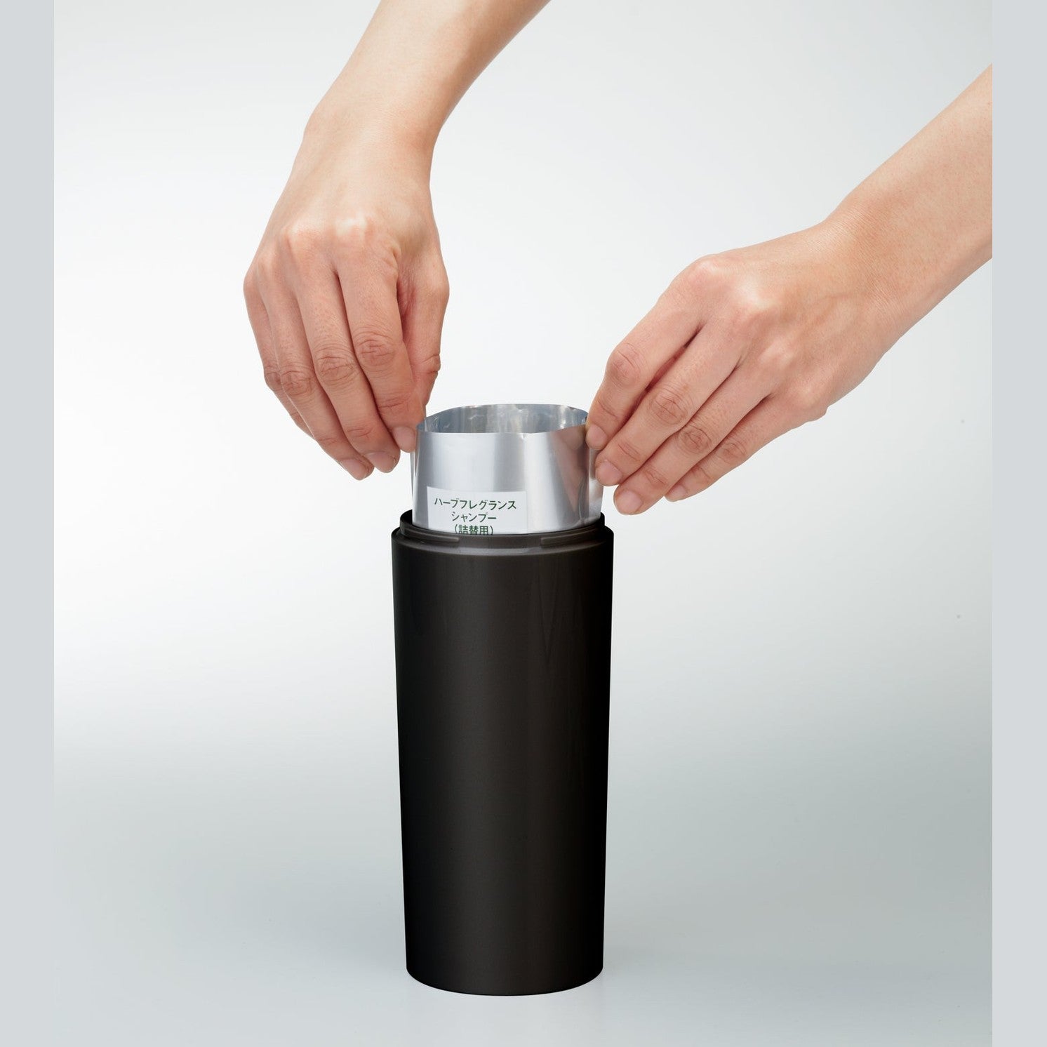 Front view of black Shampoo Dispenser on white background by Yamazaki Home.