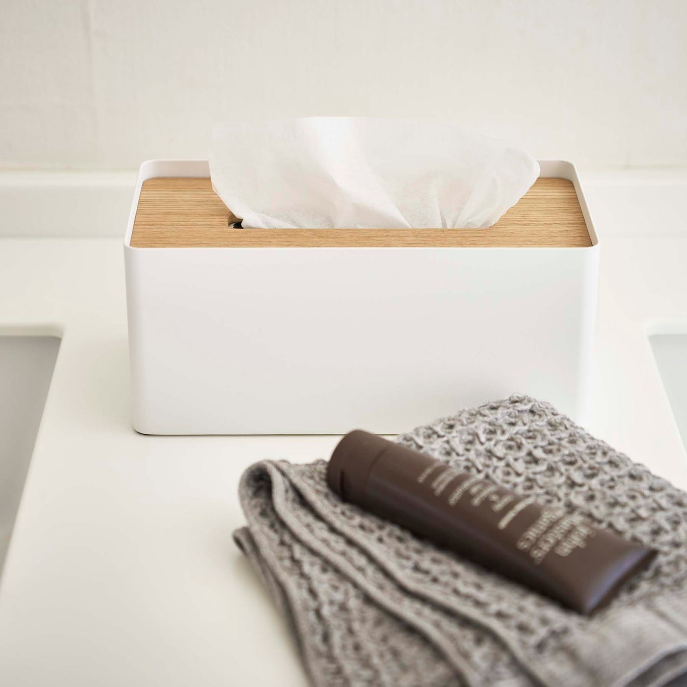 Front view of white Tissue Case on bathroom sink countertop by Yamazaki Home.