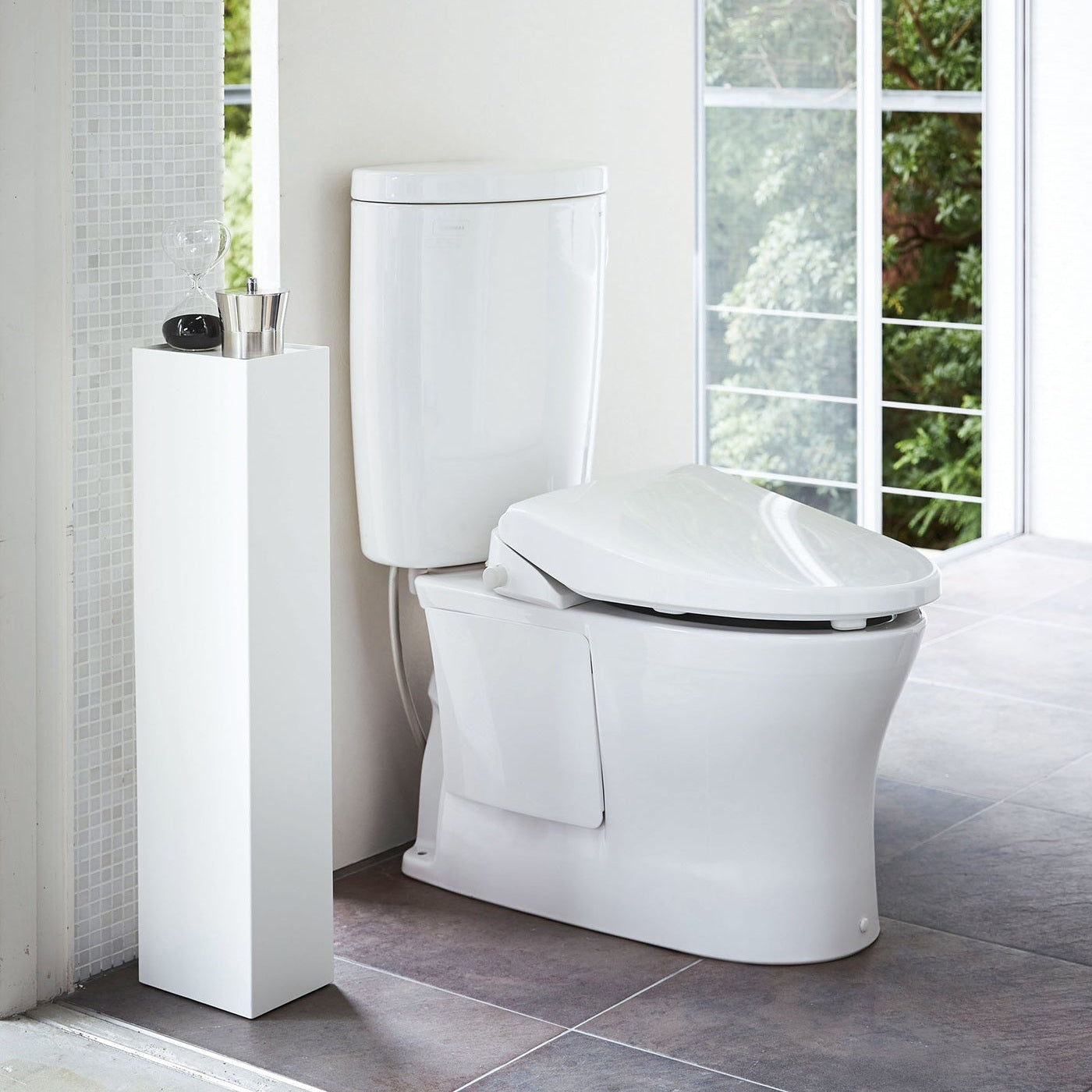 Yamazaki Home white Toilet Organizer holding decor pieces in bathroom.