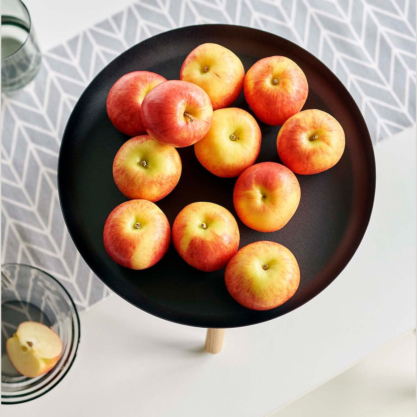 Top-down view of black Yamazaki Countertop Pedestal Tray with apples on top on a dining table