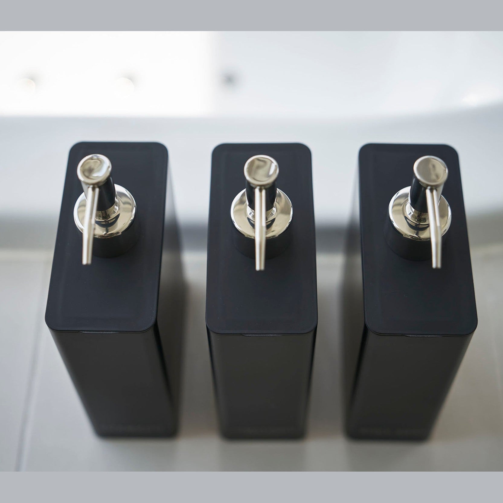 Aerial view of Yamazaki Home black Shampoo, Conditioner, and Body Soap dispensers.