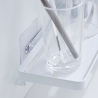 Close up of Yamazaki Home Traceless Adhesive Floating Tray with a glass resting on it