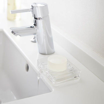 Clear Self-Draining Soap Tray holding soap on sink counter by Yamazaki Home.