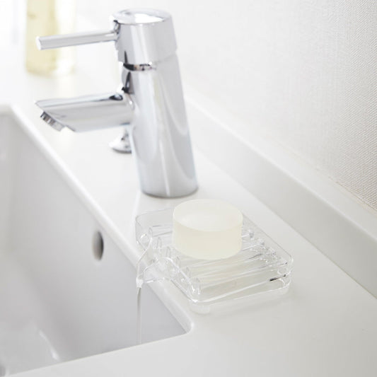 Clear Self-Draining Soap Tray holding soap on sink counter by Yamazaki Home.