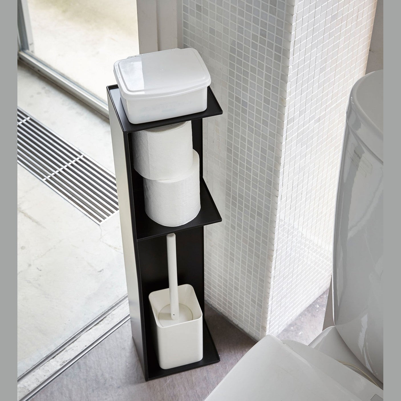 Yamazaki Home black Toilet Organizer holding toilet paper, toilet brush, and wet wipe holder in bathroom.