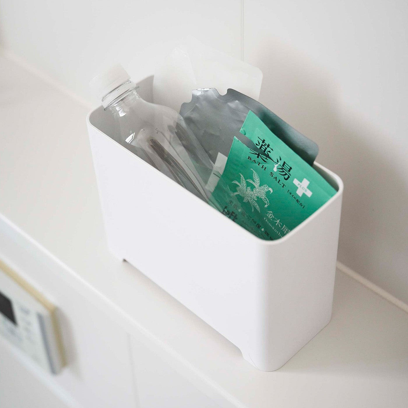 Top-down view of white Yamazaki Self-Draining Bathroom Organizer filled with bath supplies