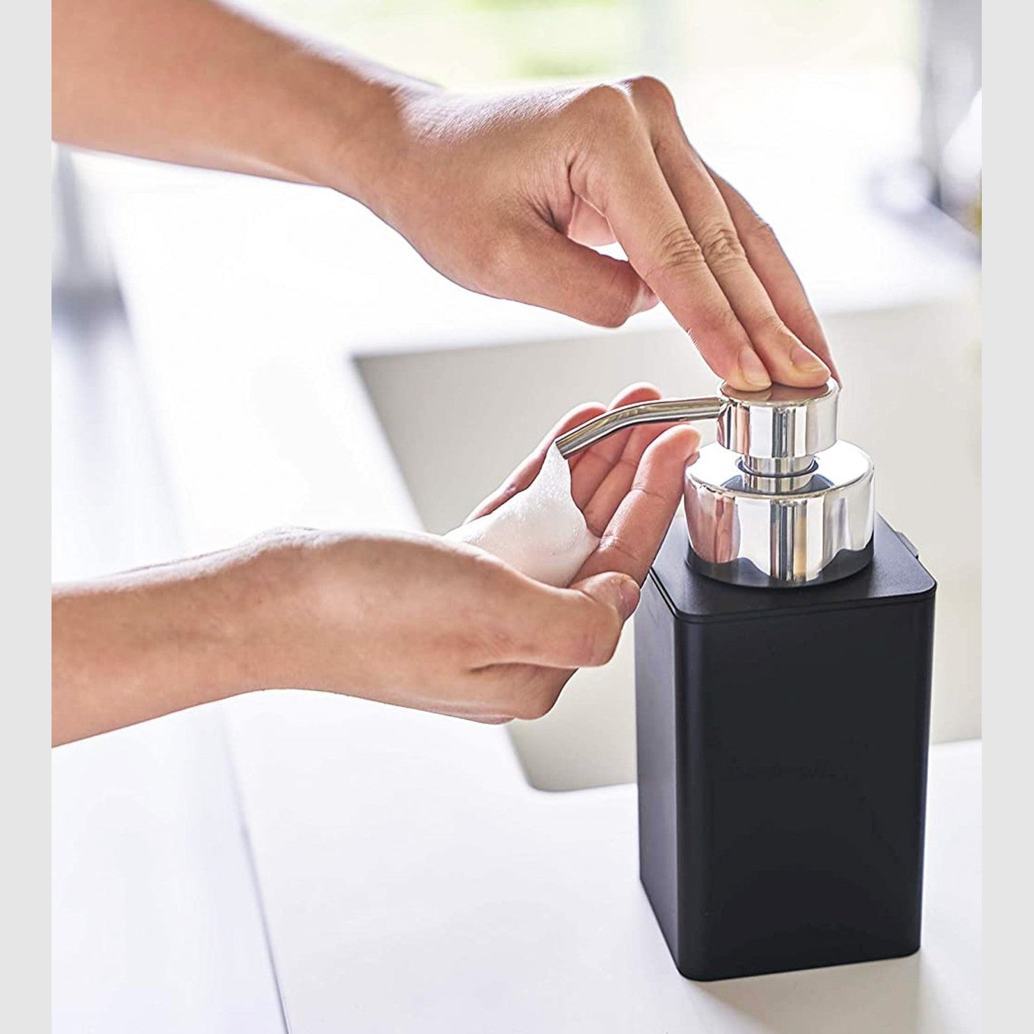 Black Foaming Soap Dispenser dispensing soap in bathroom by Yamazaki Home.