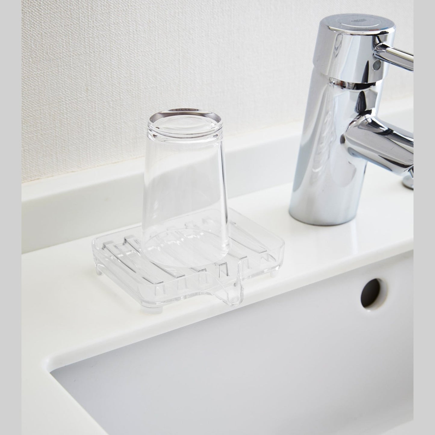 Clear Self-Draining Soap Tray holding soap bar on sink counter by Yamazaki Home.