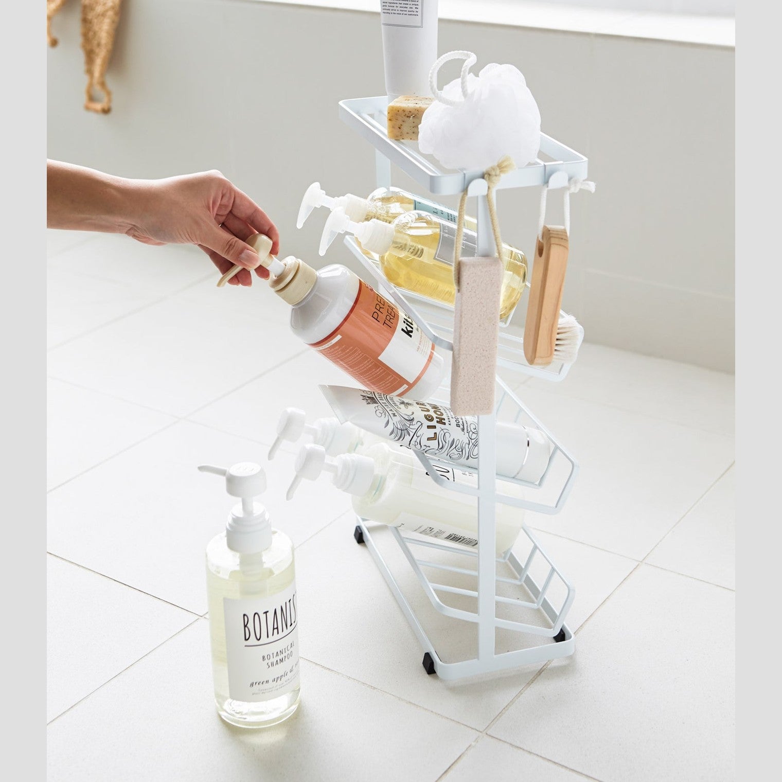 Side view of white Freestanding Shower Caddy holding shower products in bathroom by Yamazaki Home.