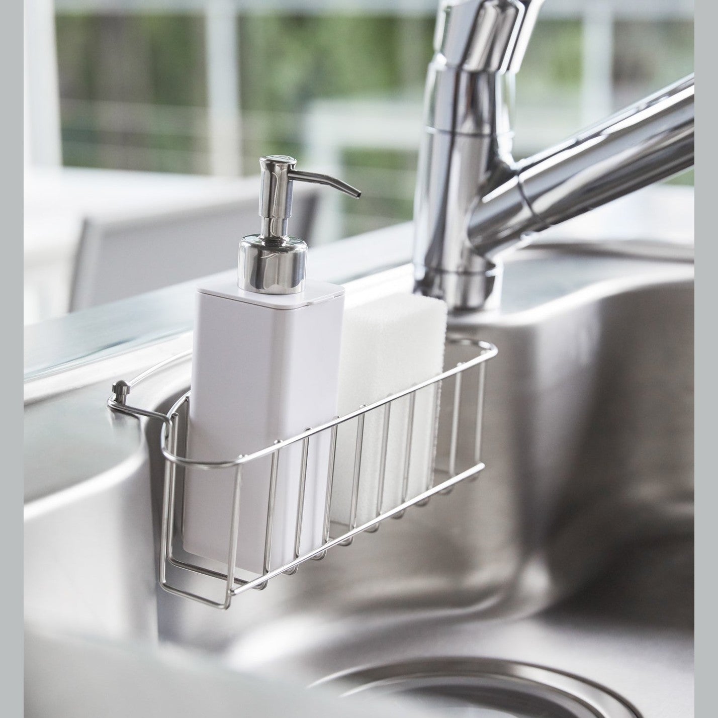 White Hand Soap Dispenser in sink tray in kitchen sink by Yamazaki Home.