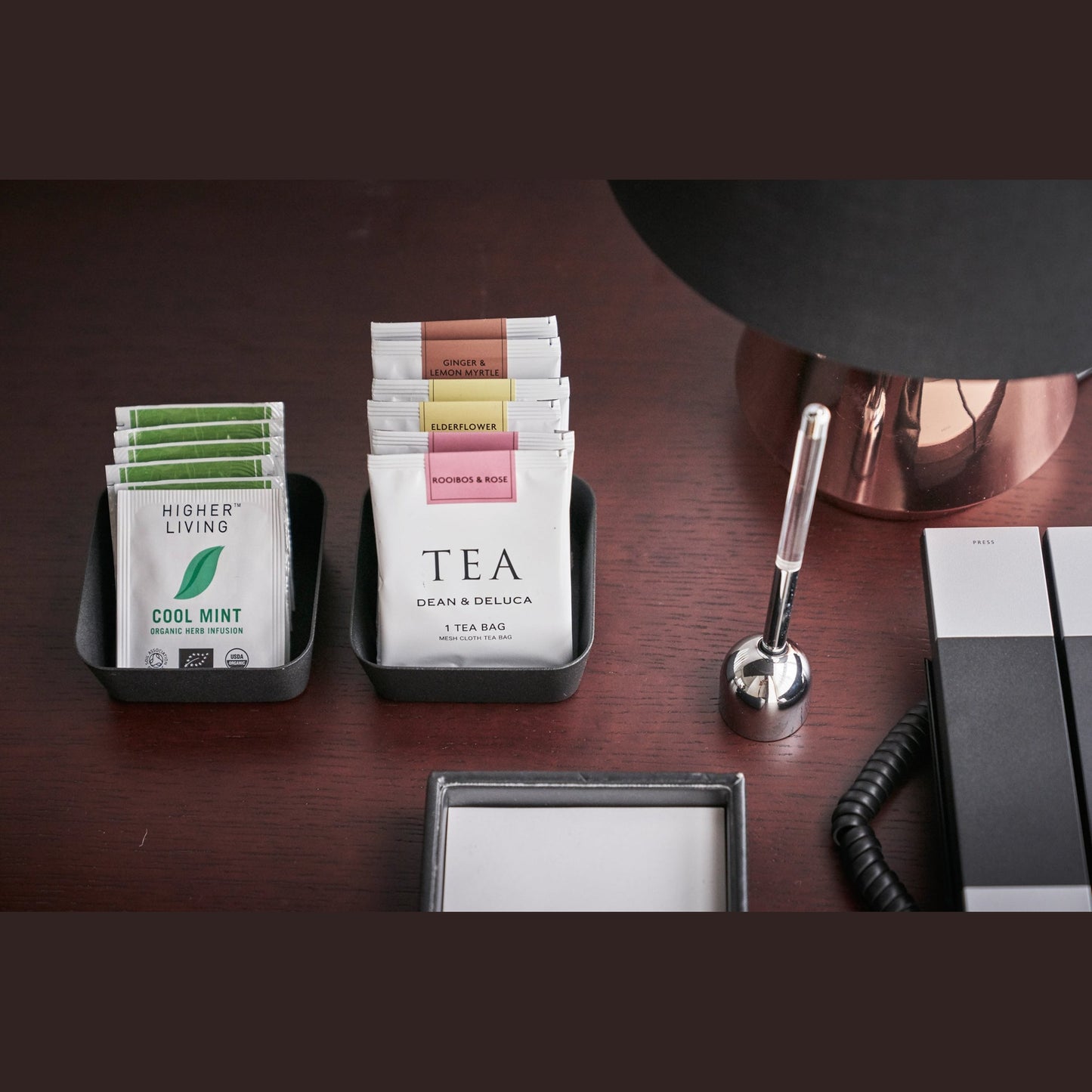 Aerial front view of black Accessory Trays holding tea bags on desk by Yamazaki Home.