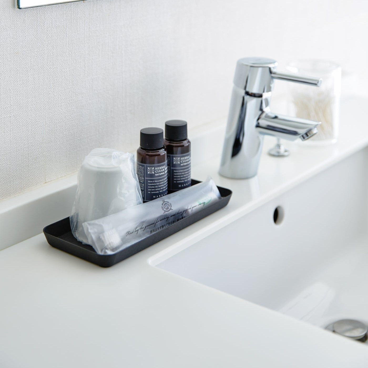 Flat black Accessory Tray holding toothbrush, cup, and soap on bathroom sink counter.