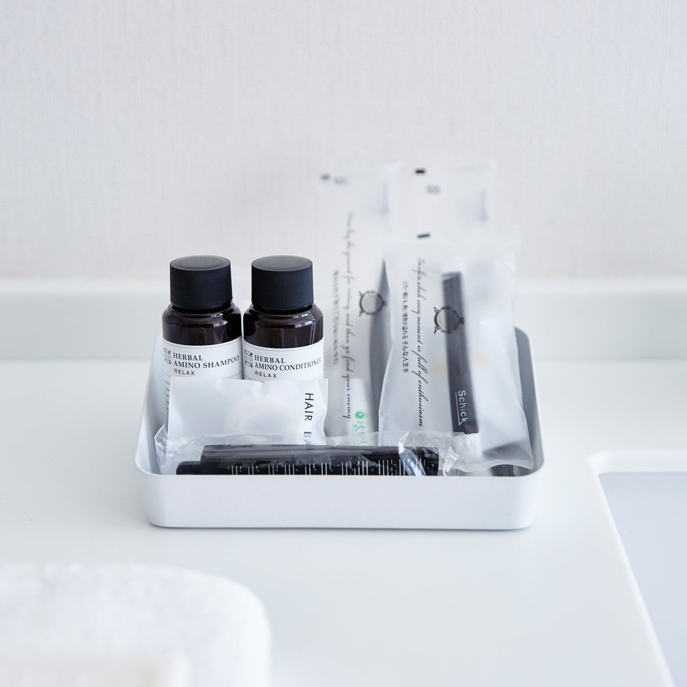 Front view of Accessory Tray holding beauty products in bathroom by Yamazaki Home.
