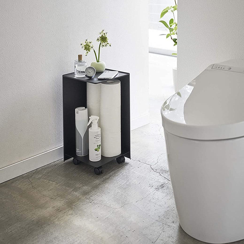 Black Rolling Bathroom Organizer holding toilet paper and supplies in bathroom by Yamazaki Home.