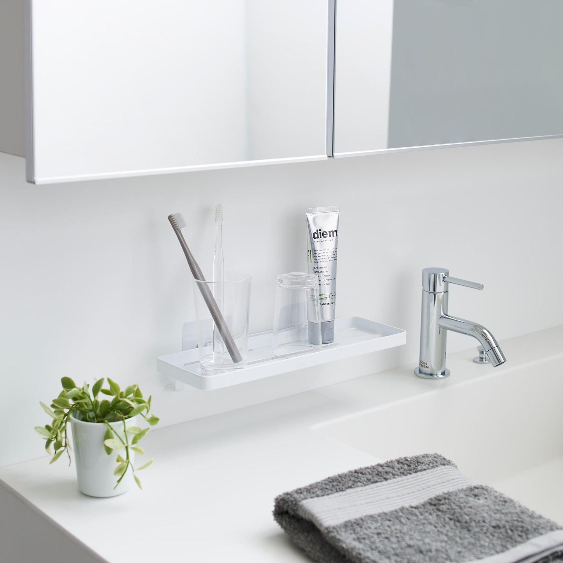Yamazaki Home Traceless Adhesive Floating Tray with a glass and toothbrush resting on it