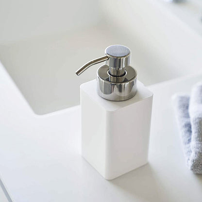 Close up view of white Foaming Soap Dispenser on sink counter by Yamazaki Home.