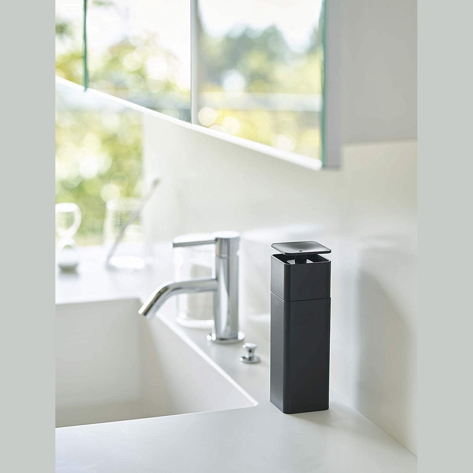 Black One-Handed Push Soap Dispenser on bathroom sink countertop by Yamazaki Home.