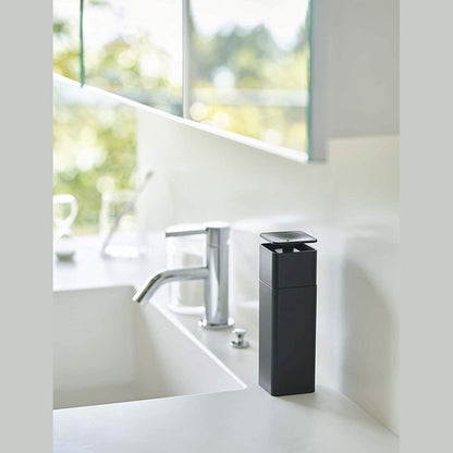 Black One-Handed Push Soap Dispenser on bathroom sink countertop by Yamazaki Home.