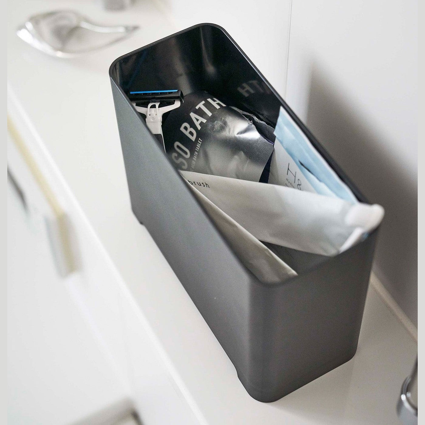 Top-down view of black Yamazaki Self-Draining Bathroom Organizer filled with bathroom products