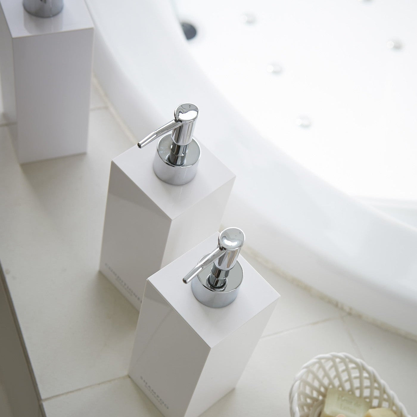 Aerial view of square soap dispenser in three styles by bathtub