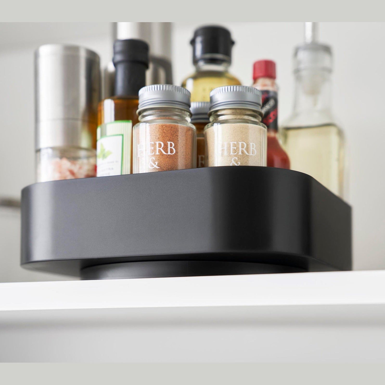 Close up of Black Yamazaki Home Rotating Storage Tray with spices and oil stored