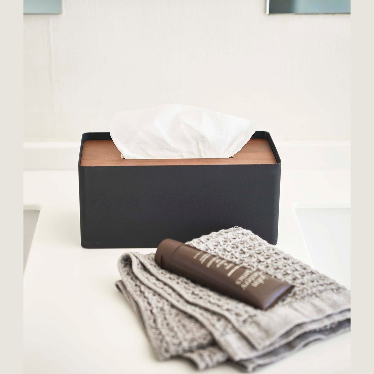 Front view of Yamazaki Home black Tissue Case holding tissues on bathroom countertop.