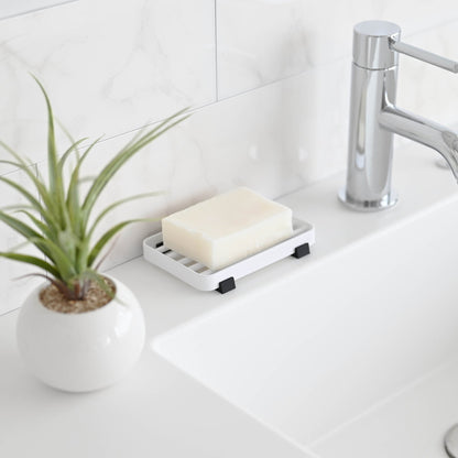 Side view of White Slotted Soap Tray holding soap bar on bathroom countertop by Yamazaki Home.
