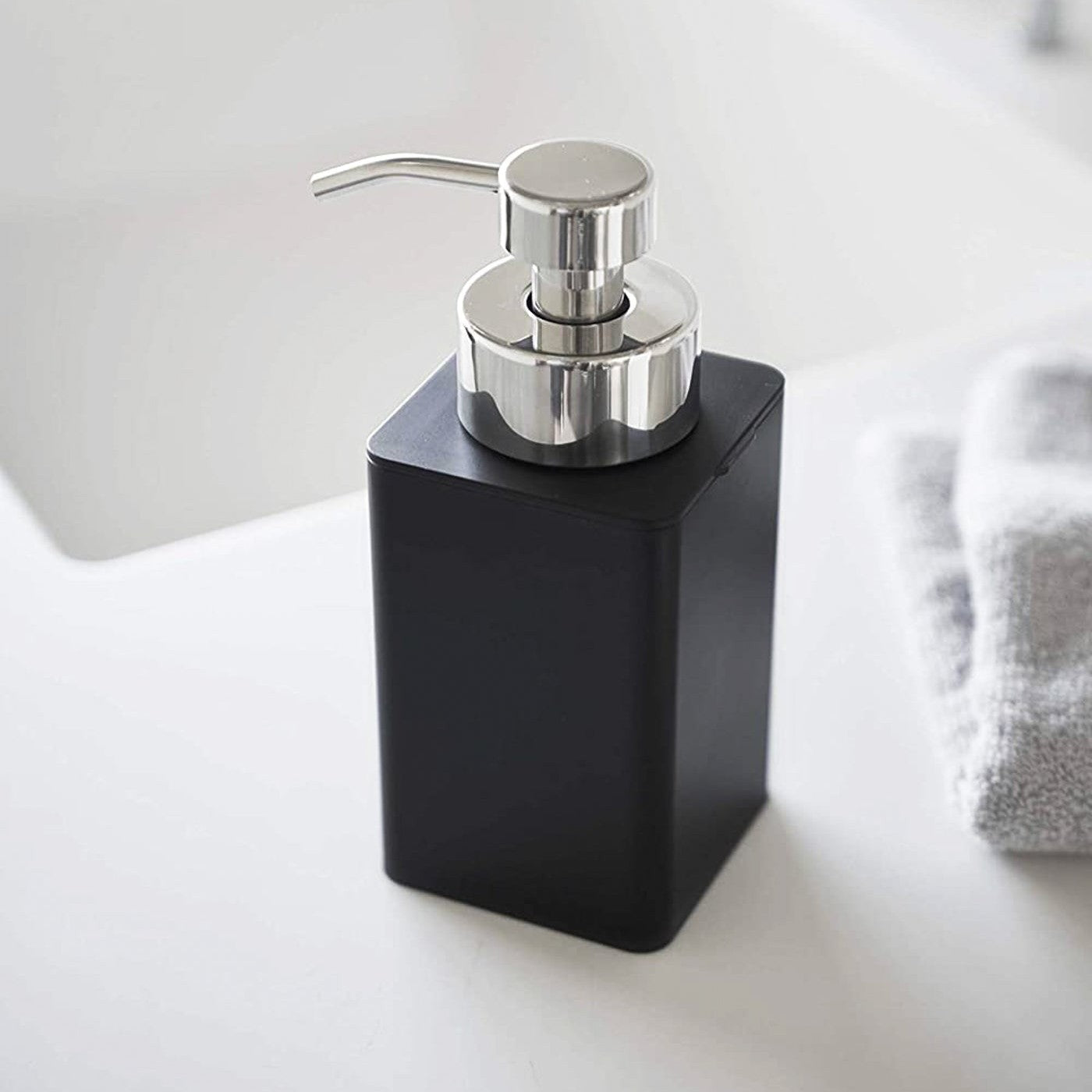 Close up view of black Foaming Soap Dispenser on sink counter by Yamazaki Home.