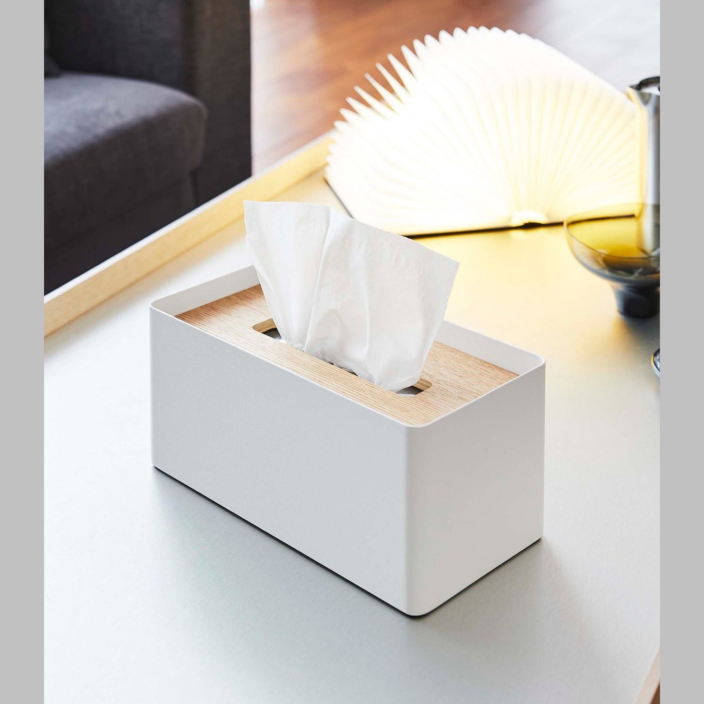 White Tissue Case next to book light on coffee table by Yamazaki Home.