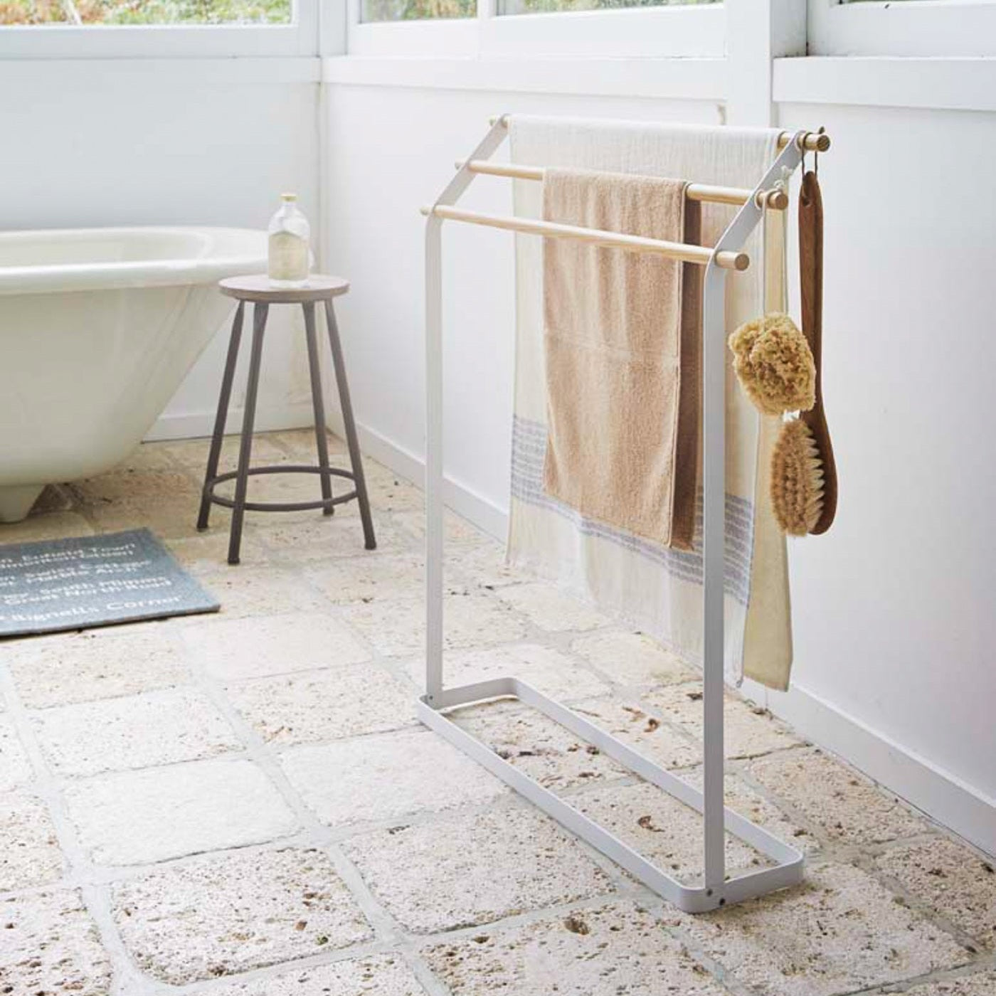 Bath Towel Rack holding towels and brushes in bathroom by Yamazaki Home.