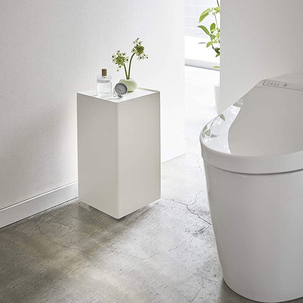 White Rolling Bathroom Organizer holding decor in bathroom by Yamazaki Home.