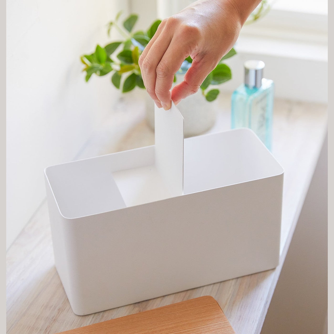 Front view of person inserting divider into white countertop organizer by Yamazaki Home.