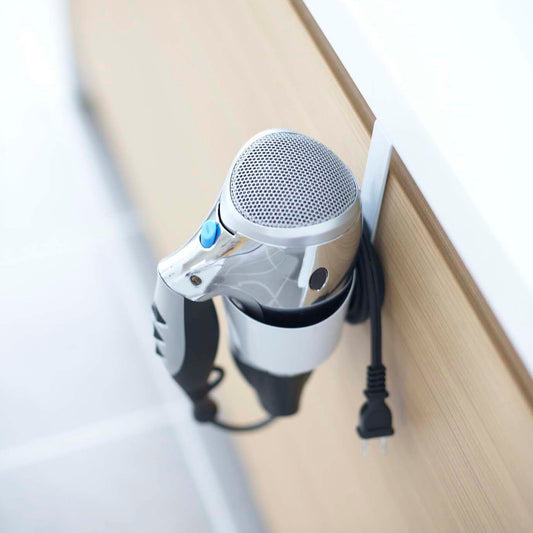 Aerial view of Blow Dryer Holder attatched to cabinet by Yamazaki Home.