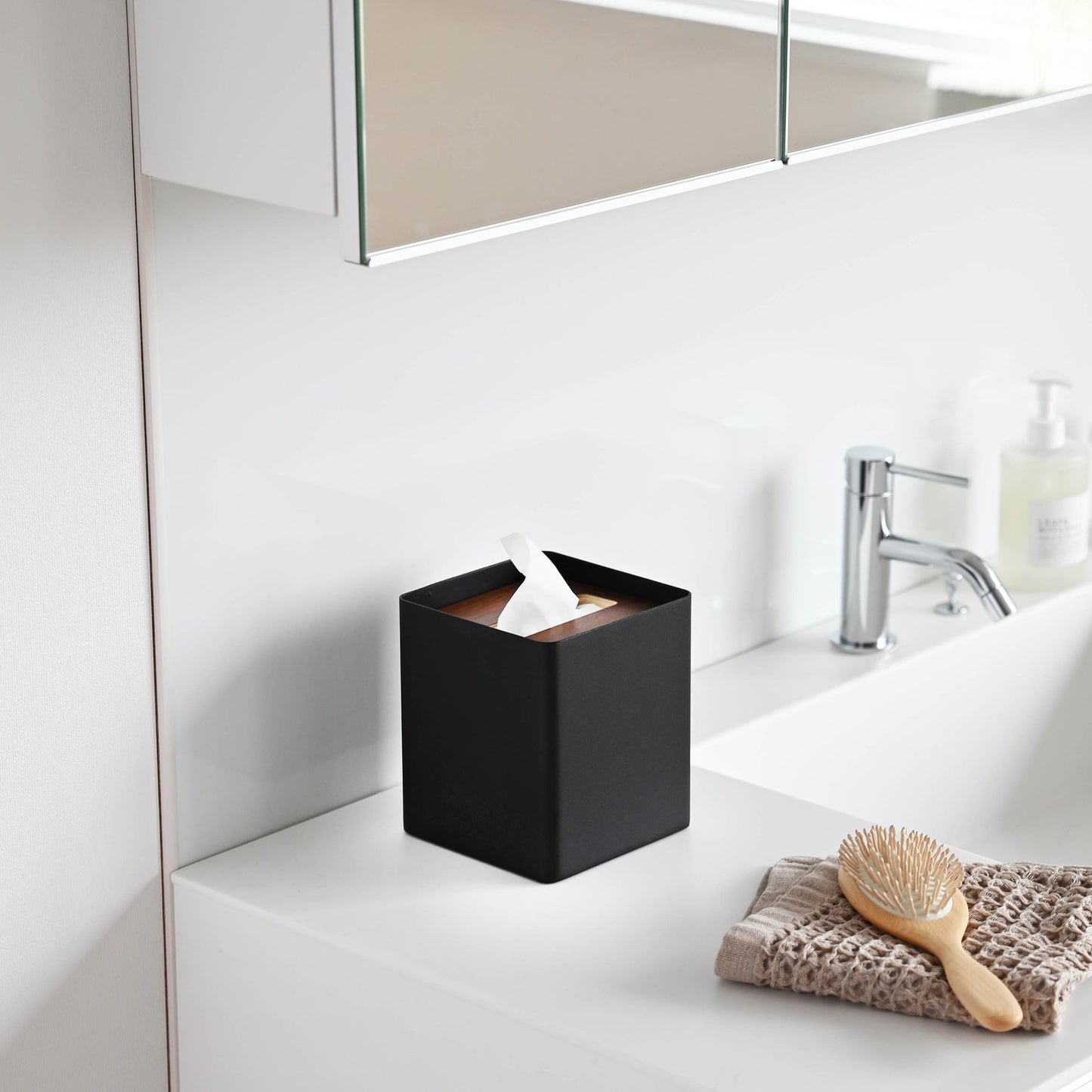 Side view of black Tissue Case on bathroom sink countertop by Yamazaki Home.