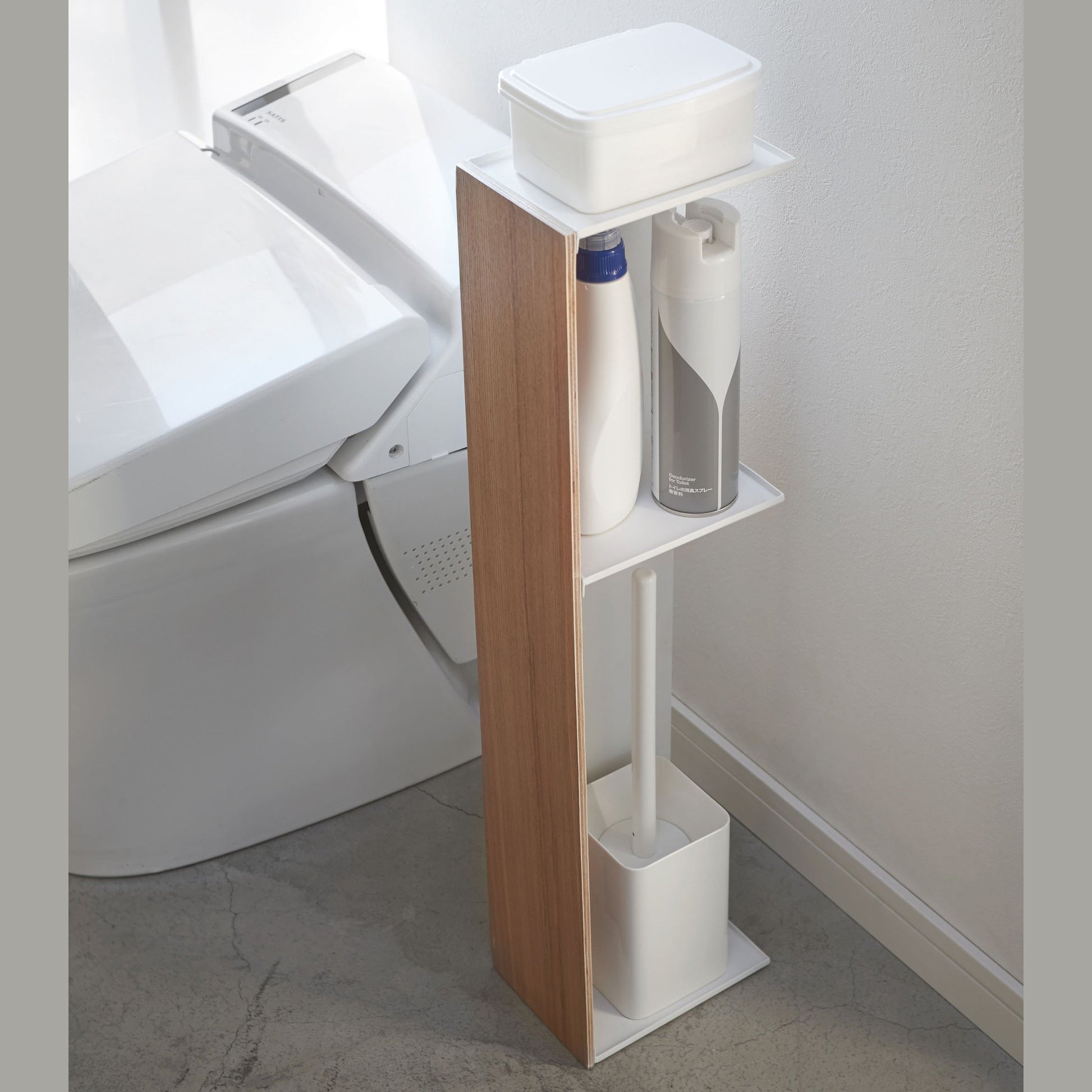 Toilet Paper Stocker holding wipe container, toilet cleaner, and toilet brush in bathroom by Yamazaki Home.