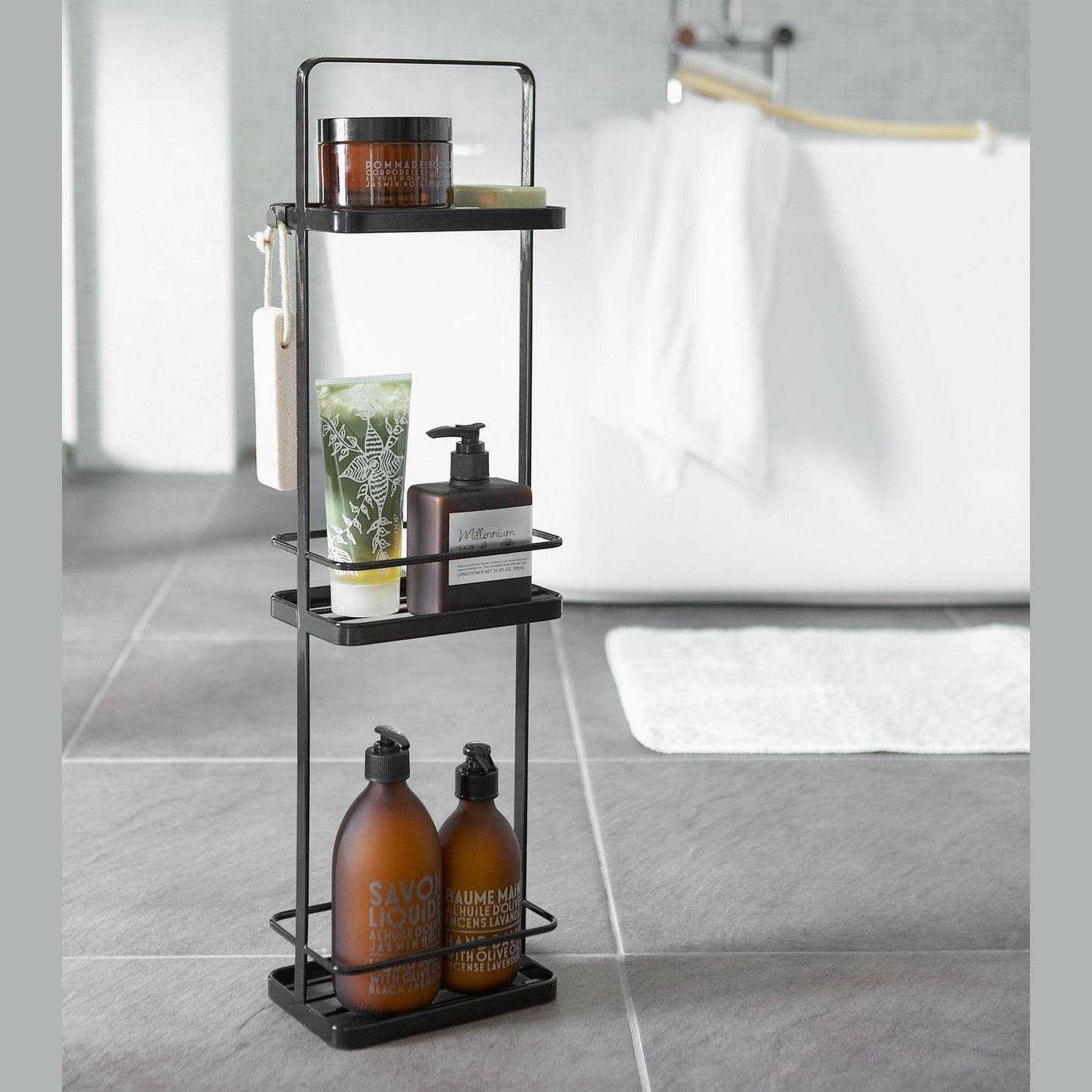 Black Portable Shower Caddy holding shower supplies in bathroom by Yamazaki Home.