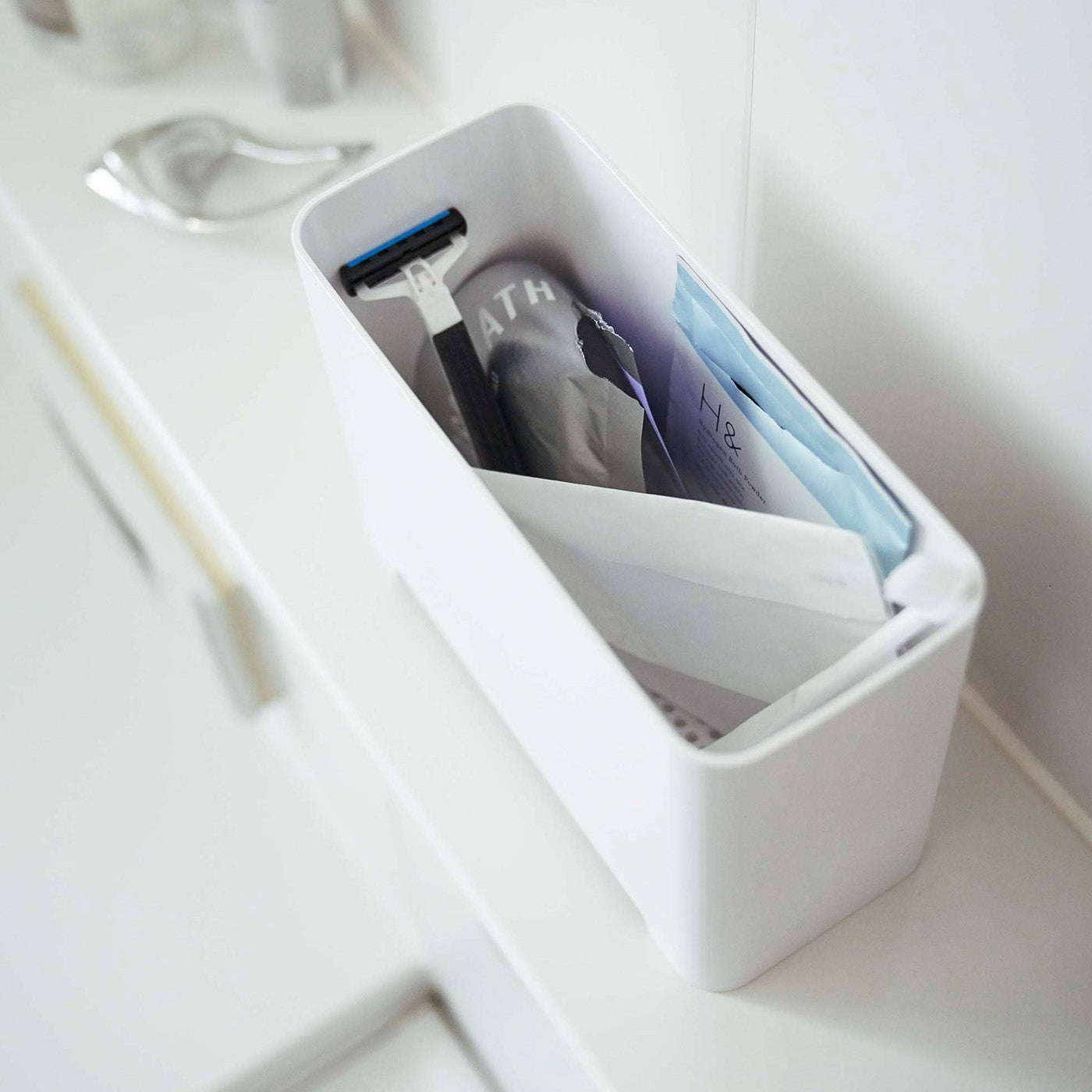 White Yamazaki Self-Draining Bathroom Organizer filled with bathroom products
