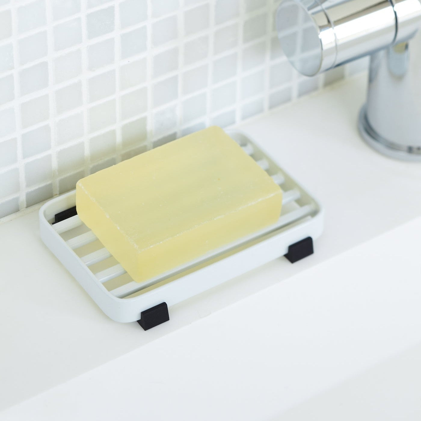 White Slotted Soap Tray on sink counter holding soap by Yamazaki Home.