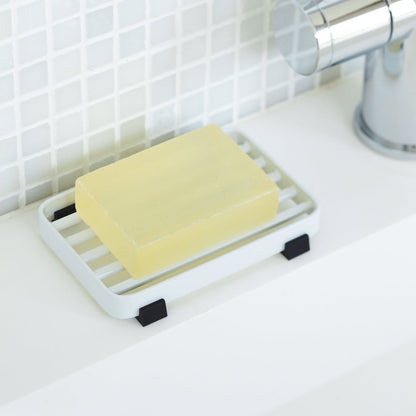 White Slotted Soap Tray on sink counter holding soap by Yamazaki Home.